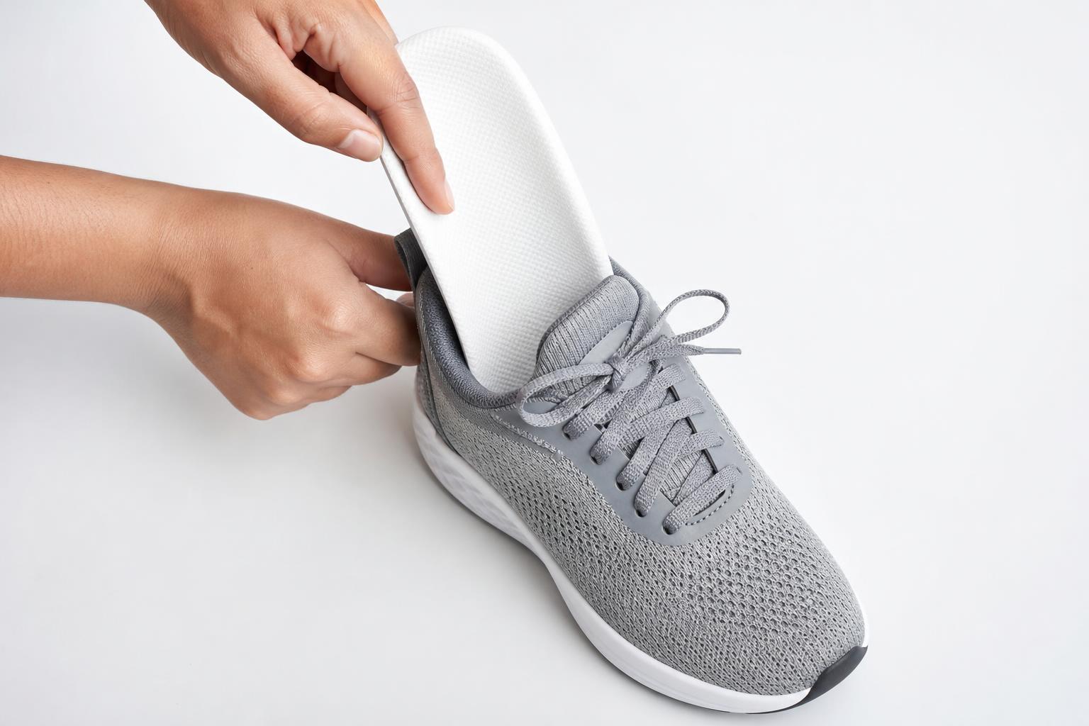 Person legt eine weiße orthopädische Einlage in einen Schuh